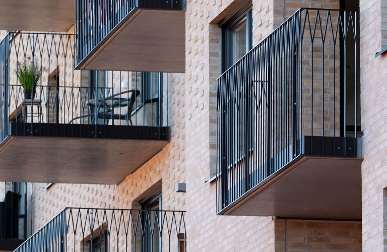 Detaljbild på bostadshus med balkonger i svart metallräcke